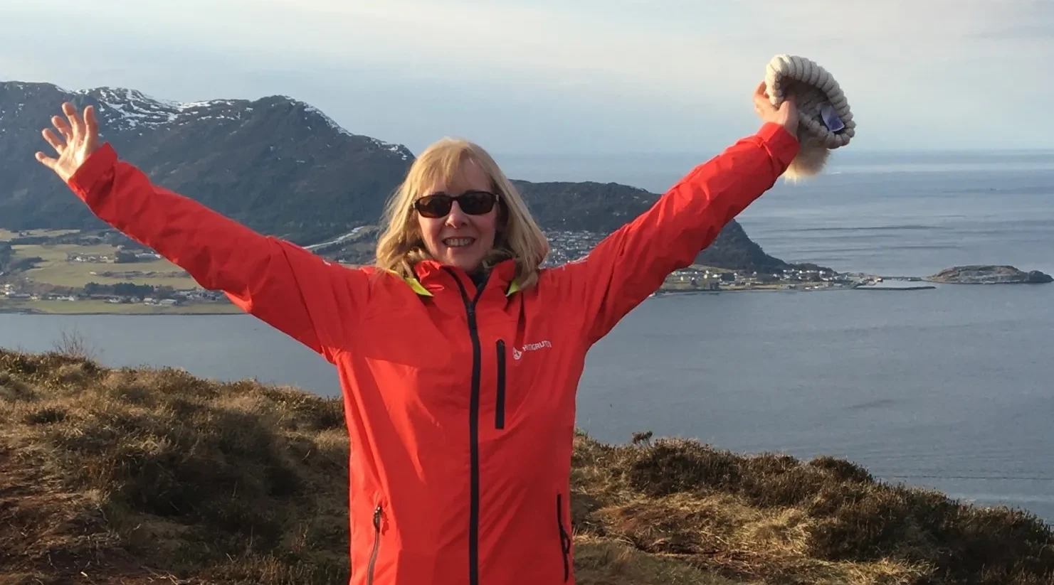 woman cheering with the sea behind her