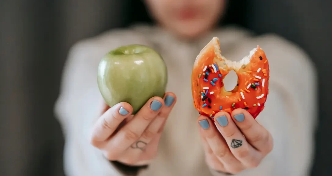 woman holding up an apple and donut